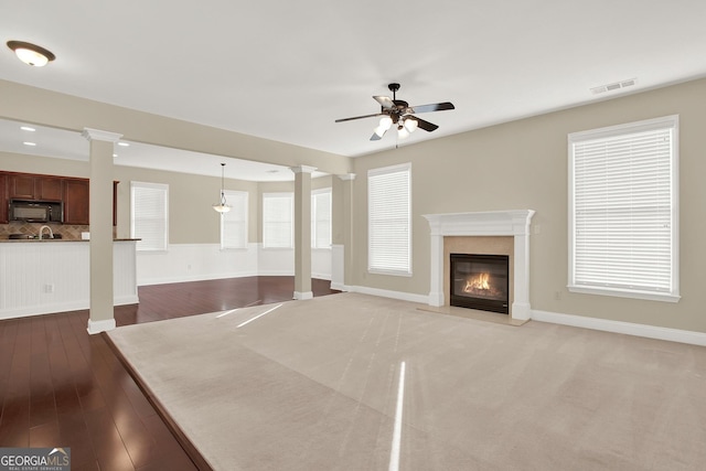 unfurnished living room featuring ceiling fan, a fireplace, and a wealth of natural light