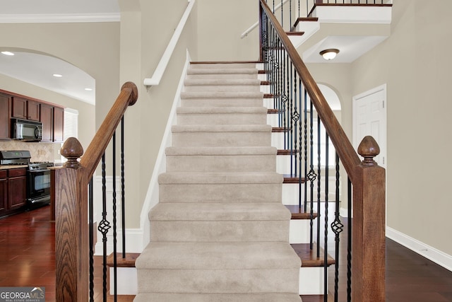 stairs with wood-type flooring and crown molding