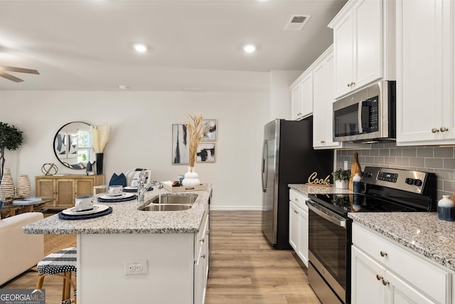 kitchen featuring sink, stainless steel appliances, white cabinetry, and an island with sink