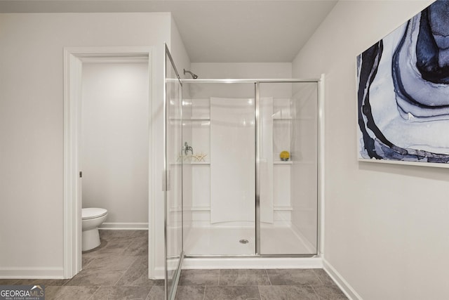 bathroom featuring toilet and a shower with shower door