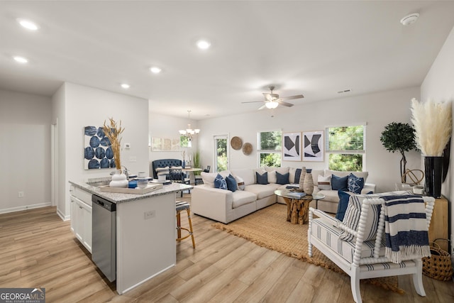 kitchen with dishwasher, white cabinets, hanging light fixtures, light hardwood / wood-style floors, and a kitchen bar