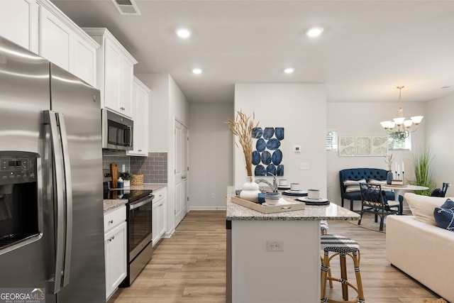 kitchen featuring white cabinets, a breakfast bar, a center island, and appliances with stainless steel finishes