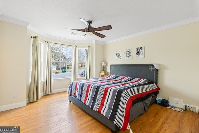 bedroom featuring baseboards, crown molding, visible vents, and wood finished floors