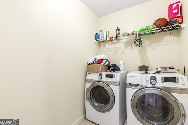 laundry area featuring laundry area, baseboards, tile patterned floors, a textured ceiling, and washing machine and dryer