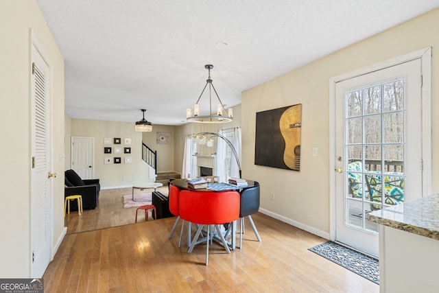 dining room featuring a chandelier, light wood-type flooring, stairway, and baseboards