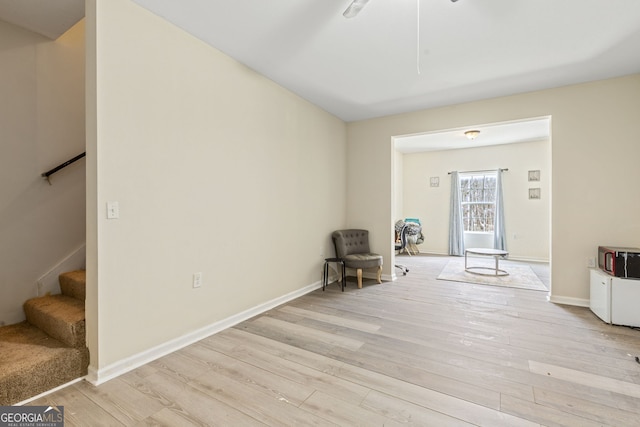 unfurnished room featuring light wood finished floors, stairs, and baseboards