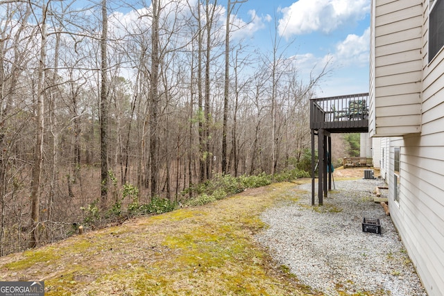 view of yard with a forest view and a wooden deck