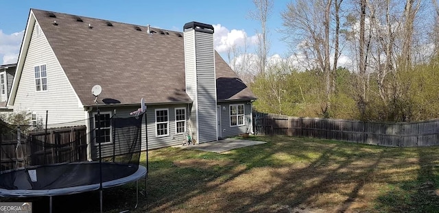 rear view of property with a patio area, a lawn, and a trampoline