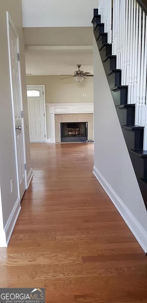 interior space featuring a tiled fireplace, ceiling fan, and hardwood / wood-style flooring