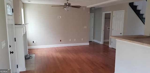 unfurnished living room with ceiling fan, dark wood-type flooring, and a textured ceiling