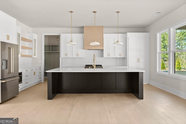 kitchen featuring white cabinetry, stainless steel appliances, pendant lighting, a kitchen island with sink, and light wood-type flooring