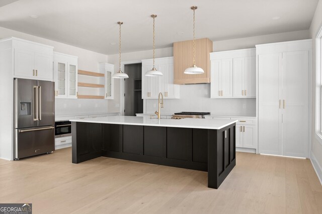 kitchen featuring stainless steel appliances, sink, a center island with sink, light hardwood / wood-style floors, and white cabinetry