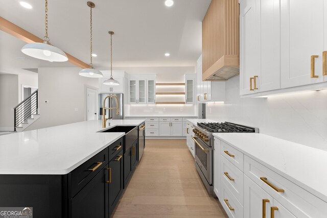 kitchen featuring white cabinets, a spacious island, hanging light fixtures, appliances with stainless steel finishes, and light hardwood / wood-style floors