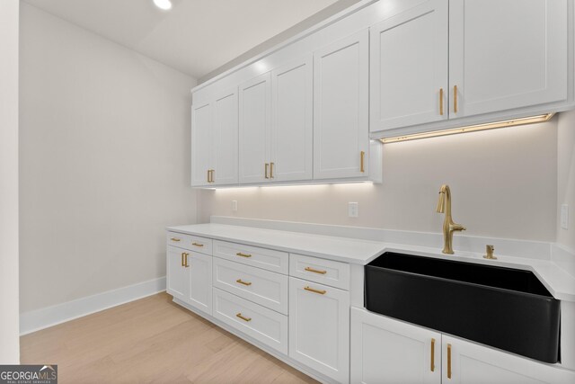 kitchen featuring white cabinetry, sink, and light hardwood / wood-style flooring