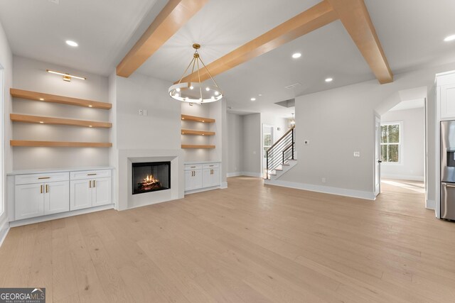 unfurnished living room with beamed ceiling and light wood-type flooring