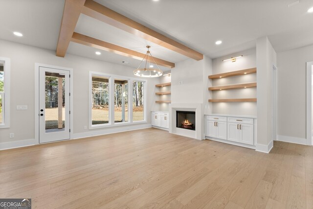 unfurnished living room with beamed ceiling, built in features, and light wood-type flooring