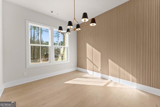 unfurnished dining area with light hardwood / wood-style flooring and an inviting chandelier