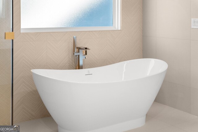 bathroom featuring tile patterned flooring, plenty of natural light, and a tub