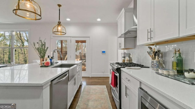 kitchen featuring appliances with stainless steel finishes, backsplash, dark hardwood / wood-style flooring, white cabinets, and hanging light fixtures