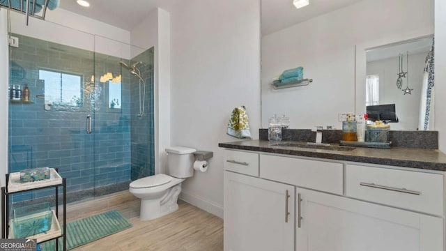 bathroom with wood-type flooring, vanity, toilet, and walk in shower