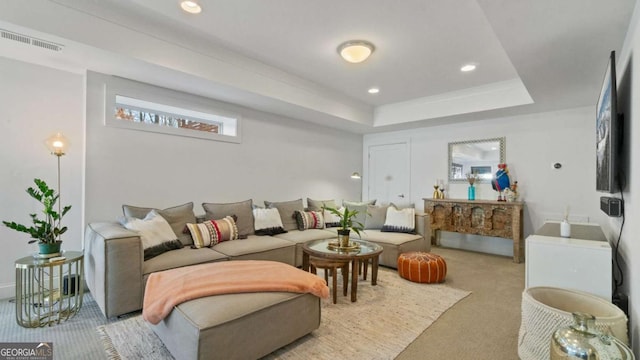 carpeted living room with a tray ceiling