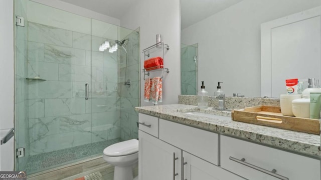 bathroom featuring an enclosed shower, vanity, and toilet