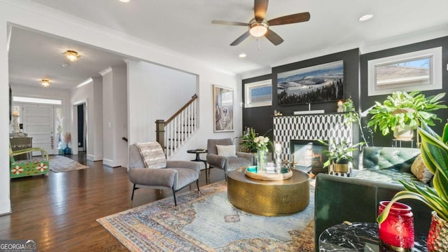 living room with ceiling fan, dark wood-type flooring, and ornamental molding