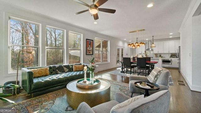 living room featuring crown molding, dark hardwood / wood-style flooring, and ceiling fan with notable chandelier