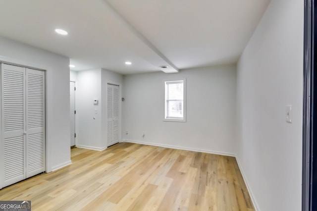 unfurnished bedroom featuring light hardwood / wood-style floors and multiple closets