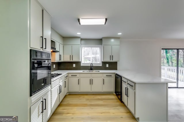 kitchen featuring kitchen peninsula, backsplash, sink, black appliances, and white cabinetry