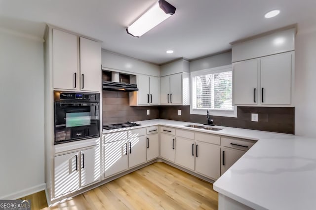 kitchen with backsplash, sink, gas stovetop, black oven, and white cabinetry