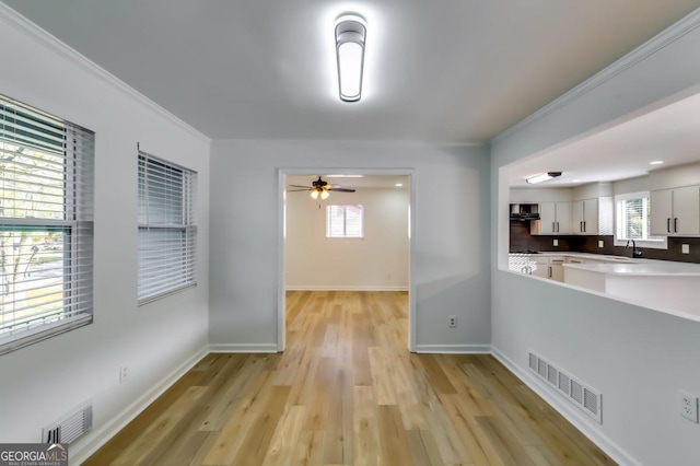 hallway featuring sink, crown molding, and light hardwood / wood-style flooring