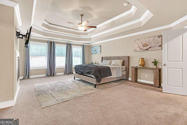 bedroom with a raised ceiling, ceiling fan, light carpet, and ornamental molding