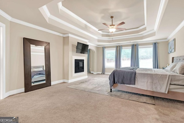 carpeted bedroom featuring ceiling fan, crown molding, and a tray ceiling