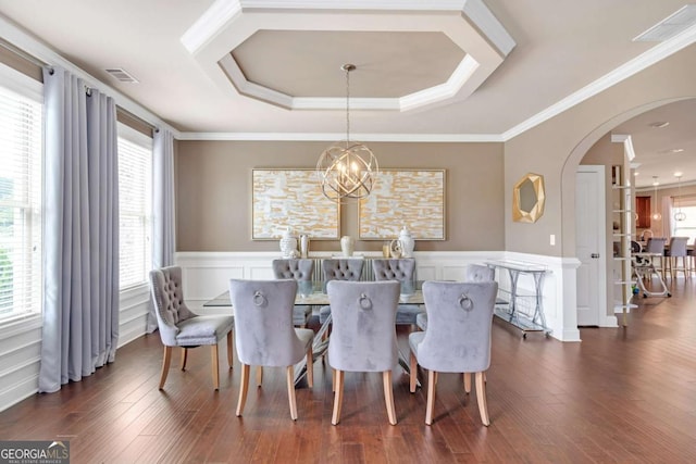 dining space featuring a raised ceiling, dark wood-type flooring, crown molding, and an inviting chandelier