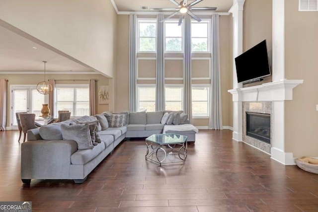 living room featuring a fireplace, plenty of natural light, dark hardwood / wood-style floors, and ceiling fan with notable chandelier