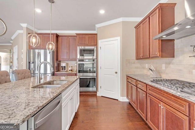 kitchen with sink, wall chimney exhaust hood, decorative light fixtures, light stone counters, and stainless steel appliances