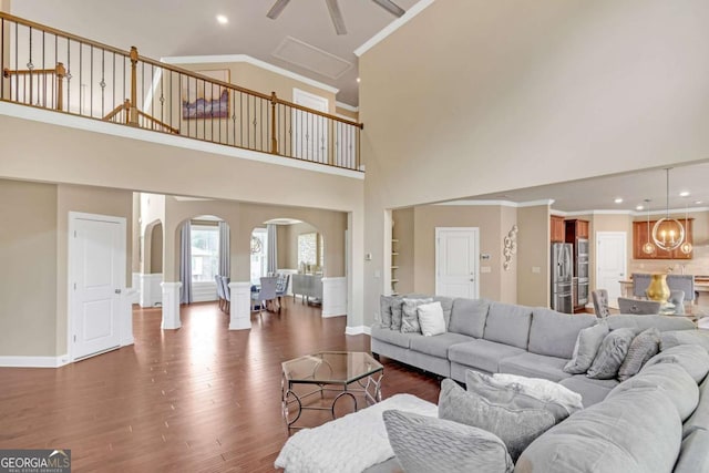 living room featuring ceiling fan, dark hardwood / wood-style floors, ornamental molding, and a high ceiling