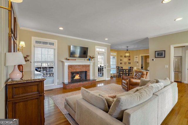 living room featuring ornamental molding, light hardwood / wood-style flooring, and a brick fireplace