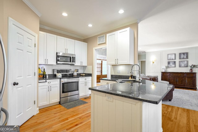 kitchen with sink, tasteful backsplash, light hardwood / wood-style floors, white cabinets, and appliances with stainless steel finishes