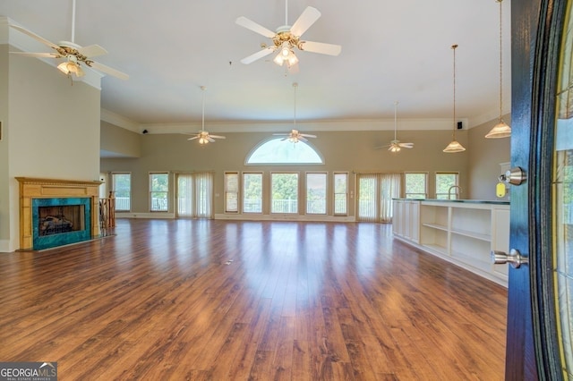 unfurnished living room featuring a towering ceiling, ornamental molding, and hardwood / wood-style flooring