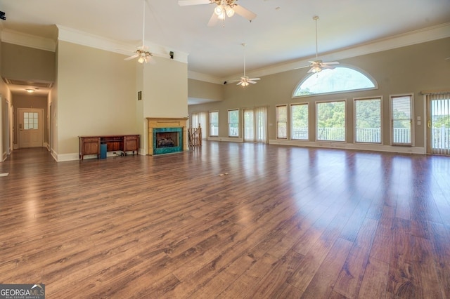 unfurnished living room featuring a tile fireplace, a high ceiling, dark hardwood / wood-style flooring, and ornamental molding