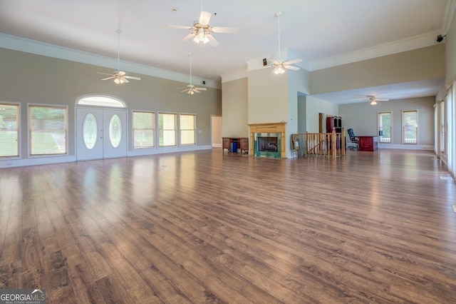 unfurnished living room featuring a towering ceiling, dark wood-type flooring, and french doors