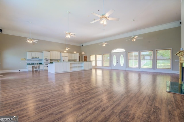 unfurnished living room featuring dark hardwood / wood-style flooring, a towering ceiling, crown molding, and a premium fireplace