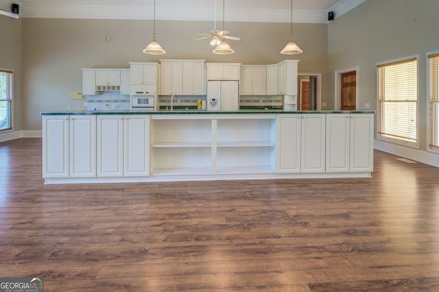 kitchen with white appliances, sink, dark hardwood / wood-style floors, tasteful backsplash, and white cabinetry