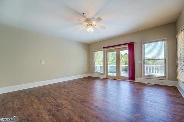 empty room with dark hardwood / wood-style flooring, a wealth of natural light, and ceiling fan