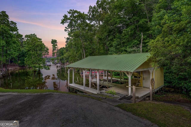 parking at dusk with a water view and a dock