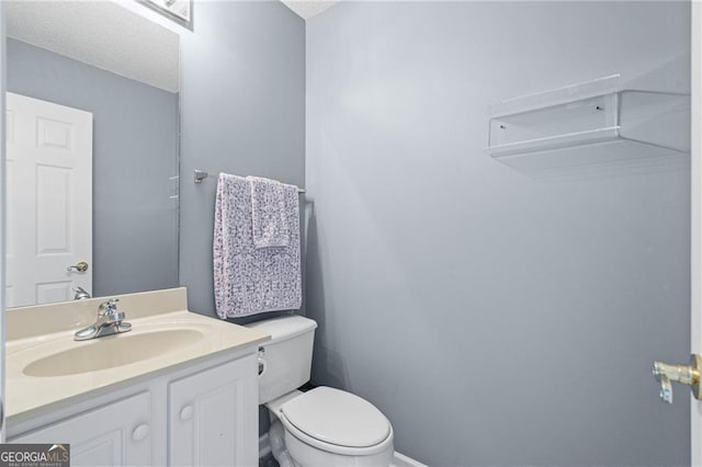 bathroom featuring vanity, a textured ceiling, and toilet