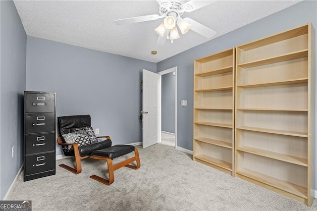 living area featuring ceiling fan, light colored carpet, and a textured ceiling