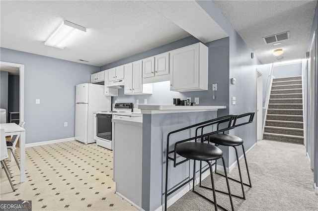 kitchen with white cabinetry, kitchen peninsula, a textured ceiling, white appliances, and a breakfast bar area